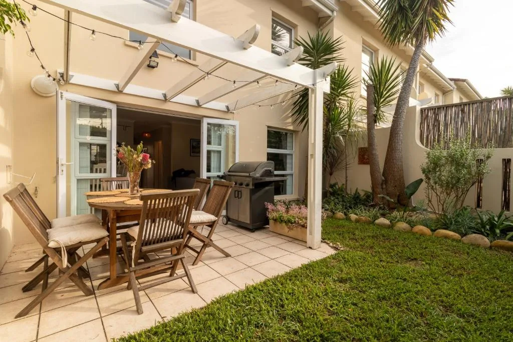 Shaded patio with dining table, braai grill, and manicured garden area