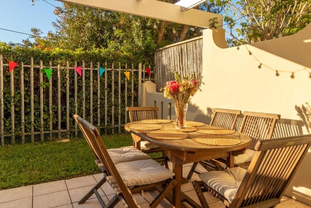 Outdoor patio with wooden dining table, chairs, and colorful bunting decorations
