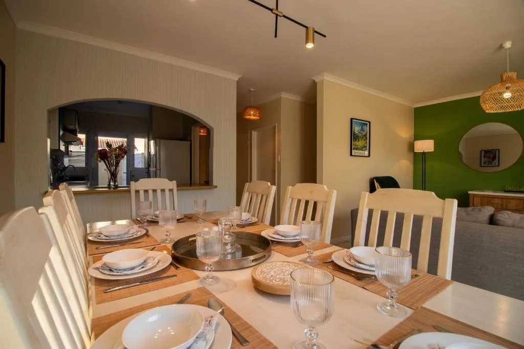 Wooden dining table set for six with white chairs and place settings
