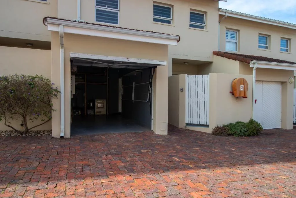 Cream-colored townhouse with brick driveway and garage entrance