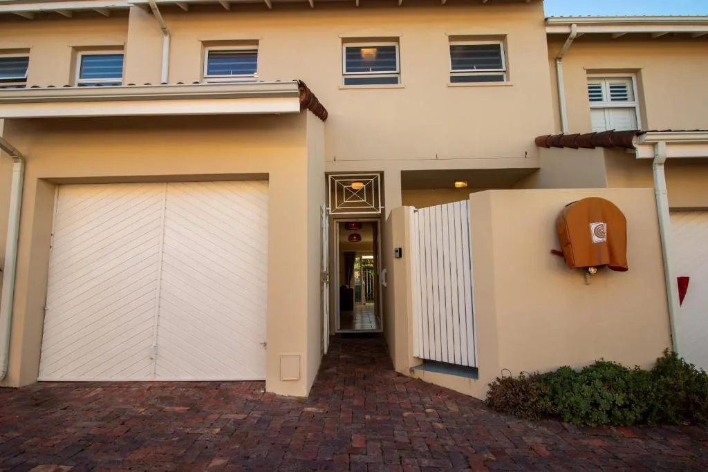 Cream-colored townhouse facade with white garage door and entrance gate