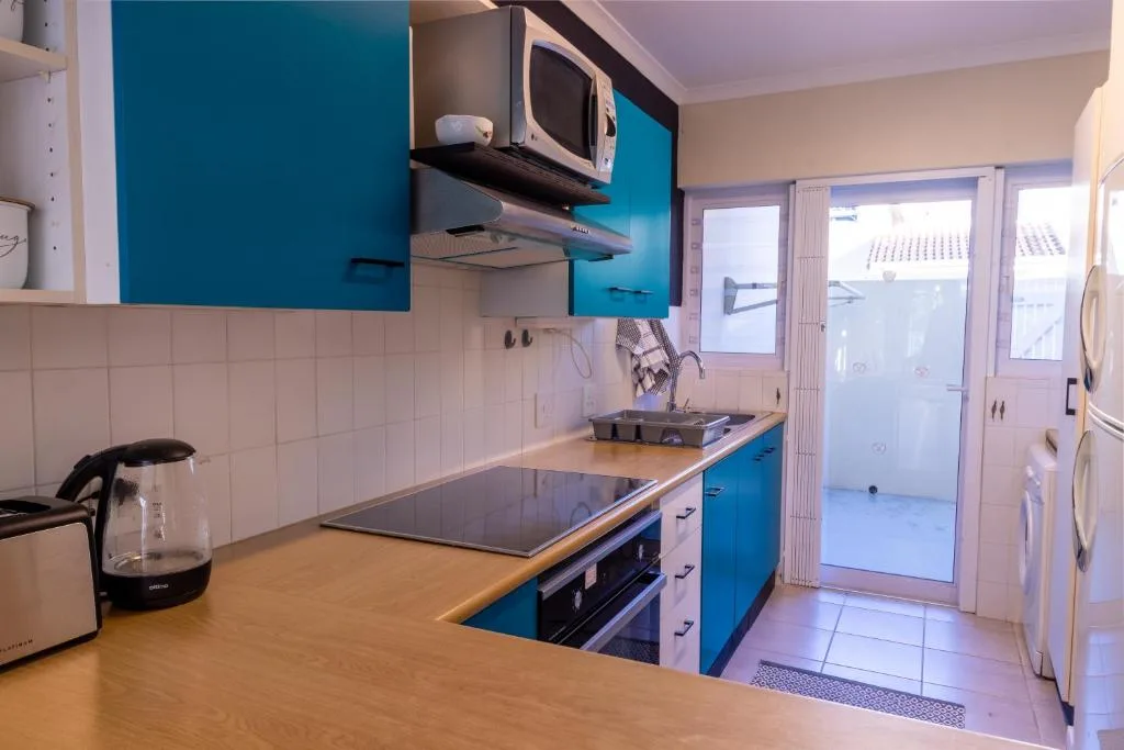 Modern kitchen with bright blue cabinets, wooden countertops, and stainless steel appliances