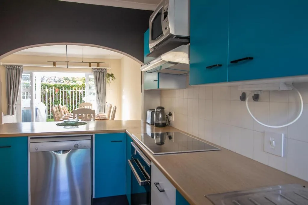 Modern kitchen with turquoise cabinetry, stainless steel appliances, and ocean view