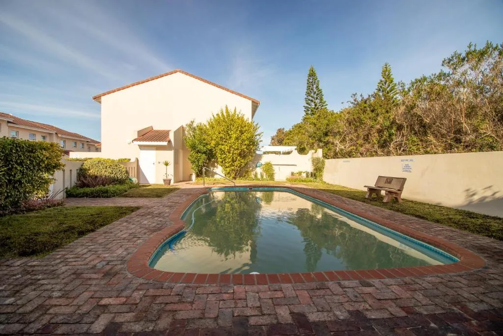 Rectangular swimming pool with brick surround and white house backdrop