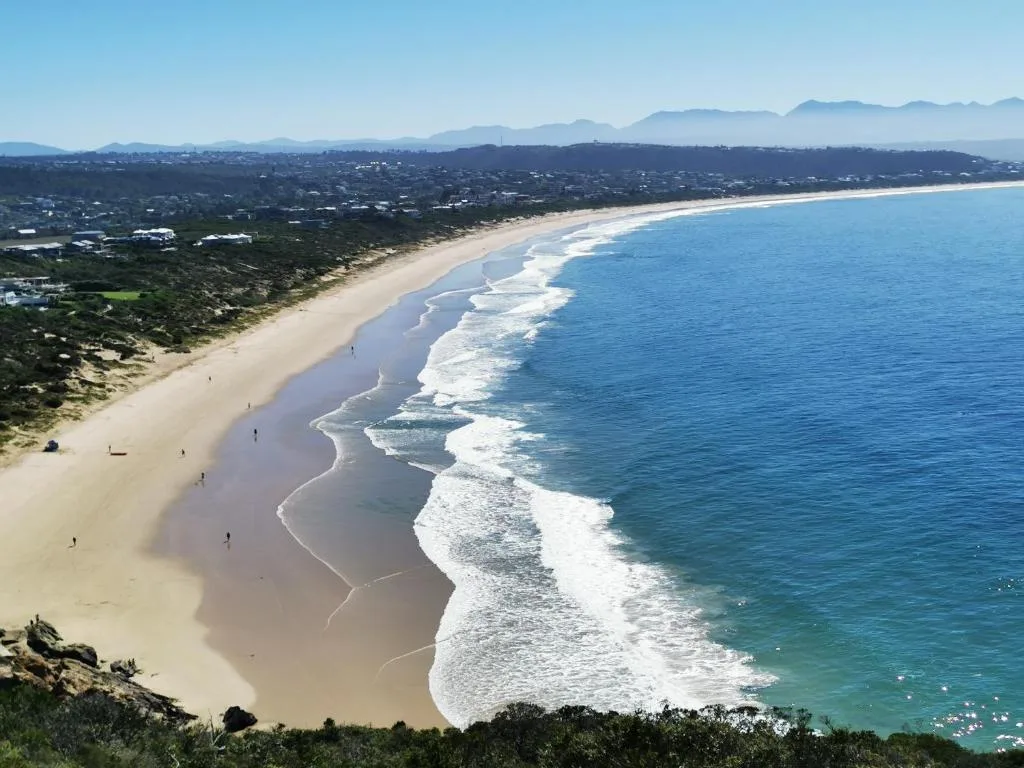 Sweeping coastal view of pristine beach with turquoise ocean and mountains