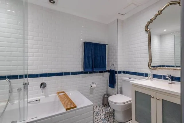 Modern bathroom with white subway tiles, bathtub, toilet, and vanity mirror