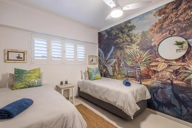 Twin bedroom with safari-themed mural and shuttered windows