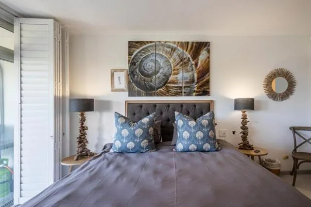 Modern bedroom with grey upholstered headboard and blue patterned pillows