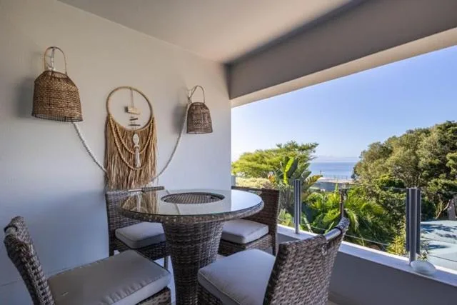 Covered deck with wicker furniture overlooking ocean and lush vegetation