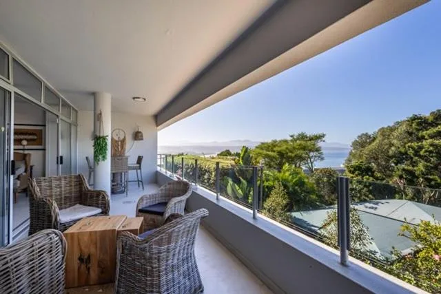 Modern covered deck with wicker seating and ocean views beyond
