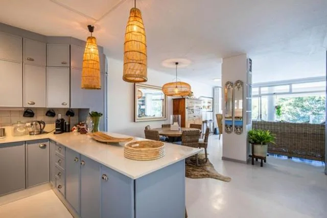 Modern kitchen with island, woven pendant lights, and open-plan living area view