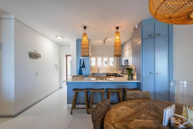Modern kitchen with blue cabinetry, pendant lights, and dining counter seating