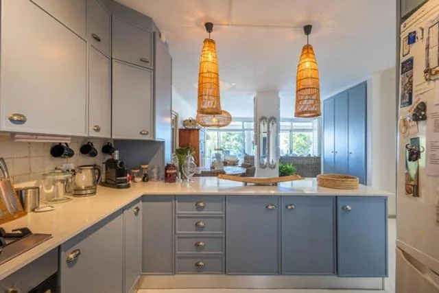 Modern kitchen with gray cabinetry, pendant lights, and white countertops