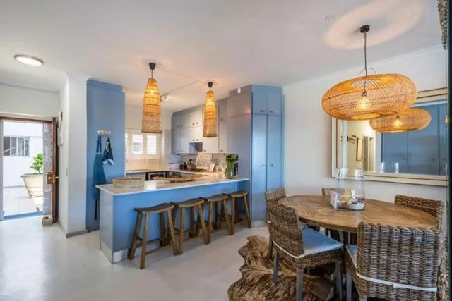 Modern blue kitchen with island seating and pendant lighting overlooking dining area