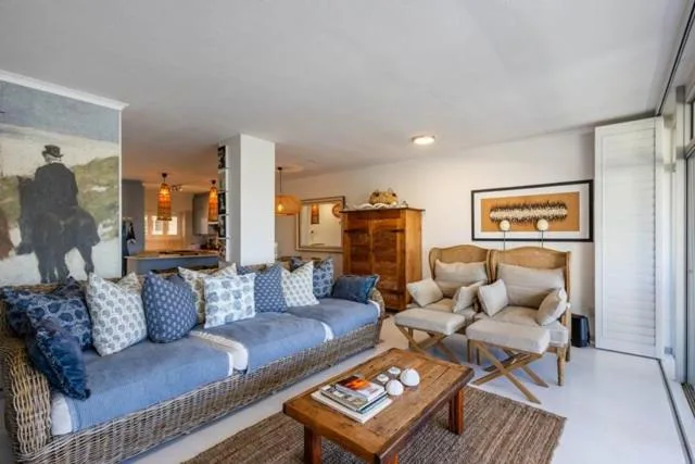 Spacious lounge with blue upholstered sofa, cream armchairs, wooden coffee table