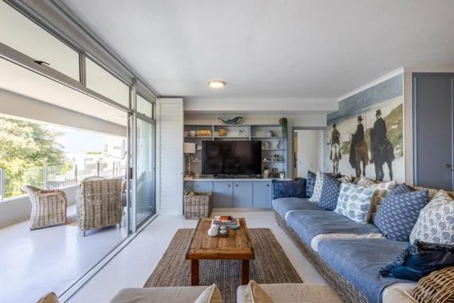 Bright living room with blue sofa, TV, and sliding doors to deck
