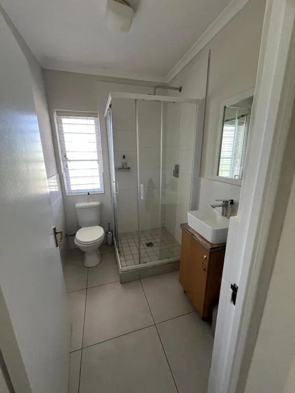 Modern bathroom with shower enclosure, toilet, and wooden vanity sink