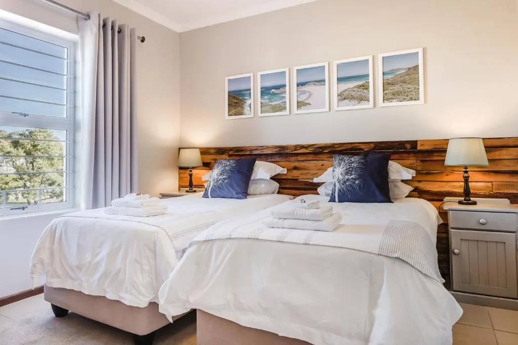 Twin beds with white linens and coastal landscape artwork above headboard