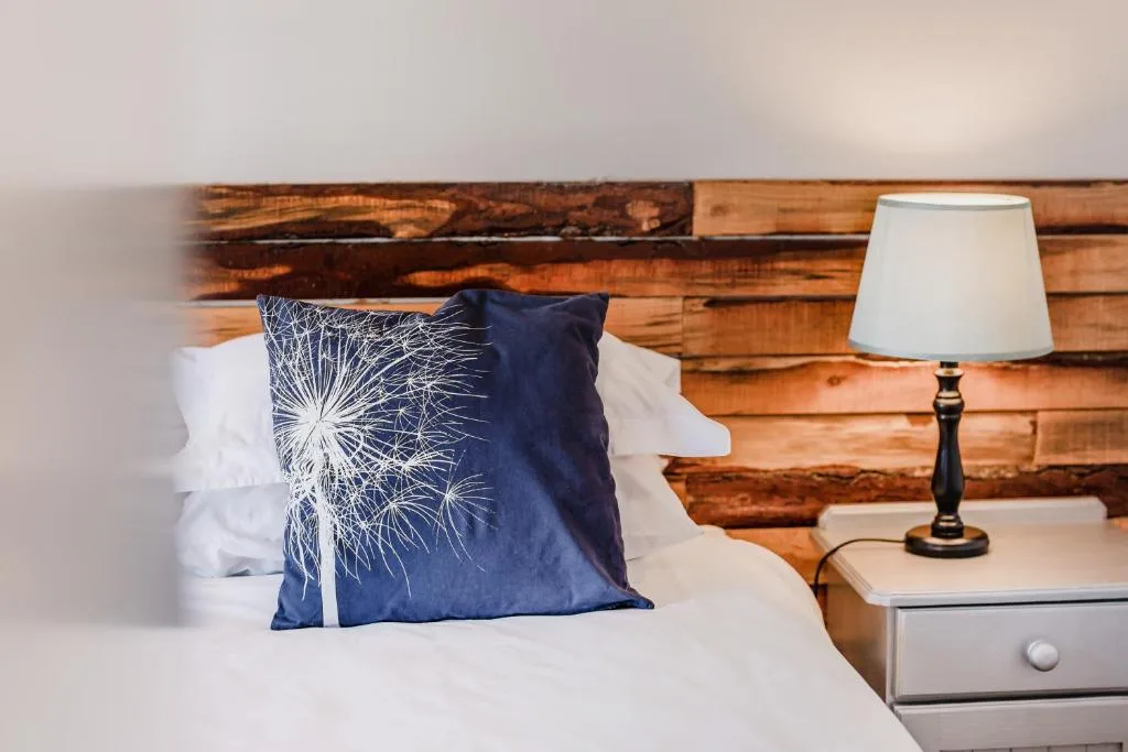 Bed with blue patterned pillow and rustic wooden headboard detail