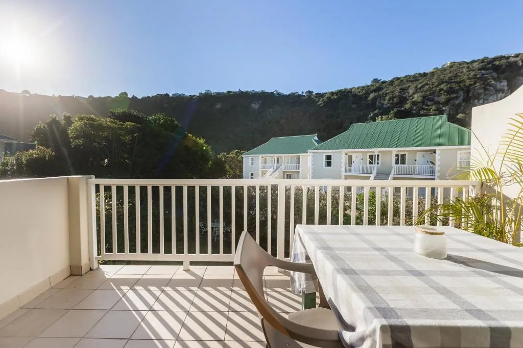 Sunny deck with white railing overlooking mountains and garden below
