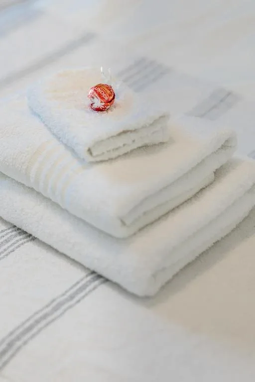 Stacked white towels with decorative red ornament on bed