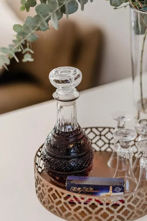 Elegant crystal decanter with decorative vessel beside potted plants indoors