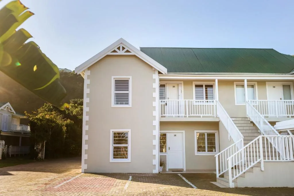 Modern cream-colored residential building with green roof and white railings