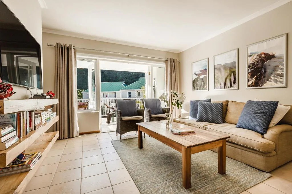 Bright lounge with beige sofa, armchairs, wooden coffee table, and garden views