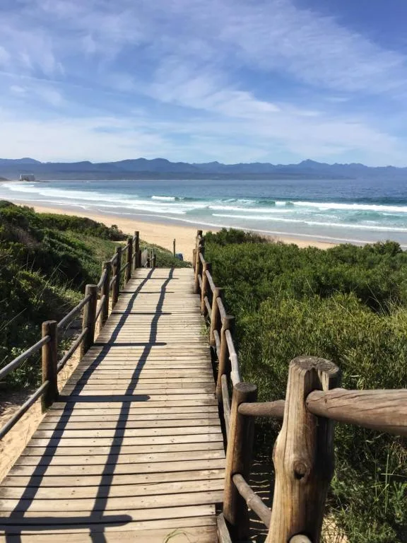 Sandy beach with mountains beyond, accessed via wooden boardwalk