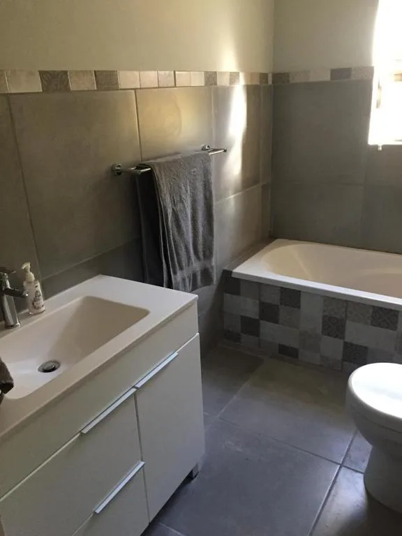 Modern bathroom with white vanity, bathtub, and tiled walls