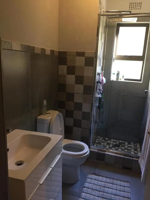 Modern bathroom with toilet, sink, and enclosed shower stall