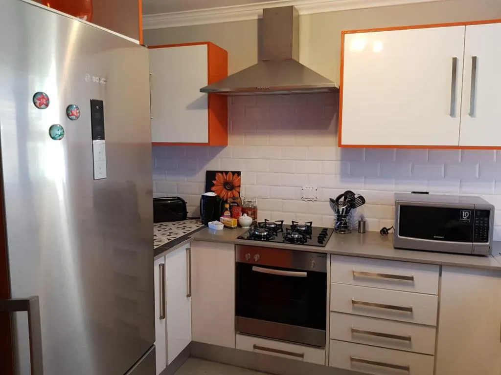 Modern kitchen with stainless steel appliances and orange accents