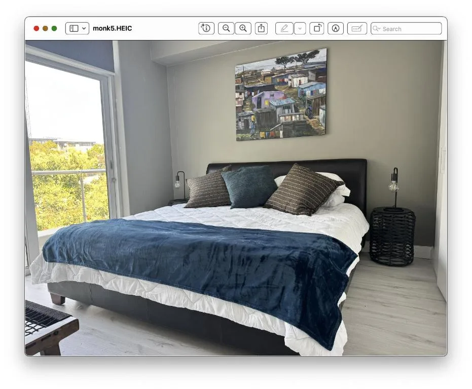 Bright modern bedroom with queen bed, navy bedding, and large window