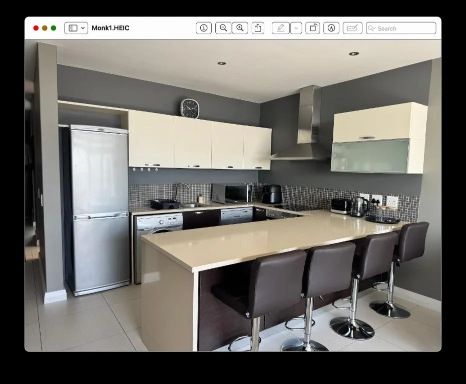 Modern kitchen with cream cabinets, black countertop, island seating for three