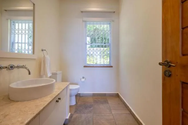 Modern bathroom with round vessel sink, toilet, and natural light from window