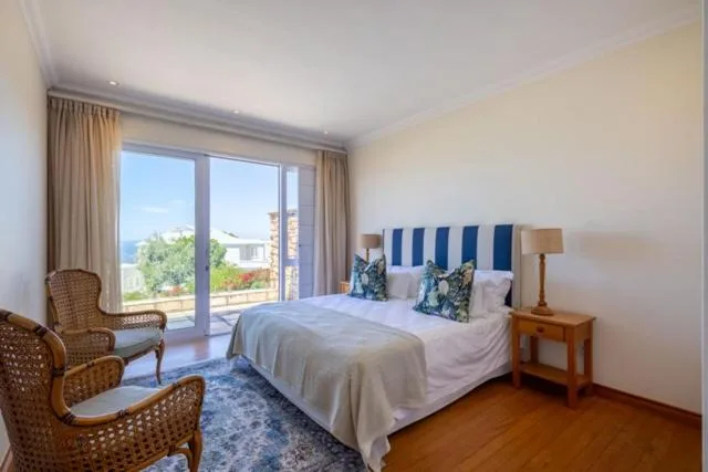 Bright bedroom with queen bed, sea view through glass doors, wicker chairs