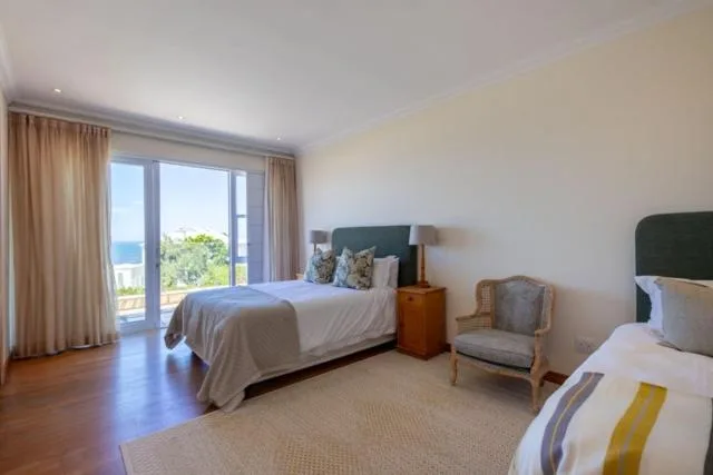 Spacious bedroom with ocean views through glass doors and two beds