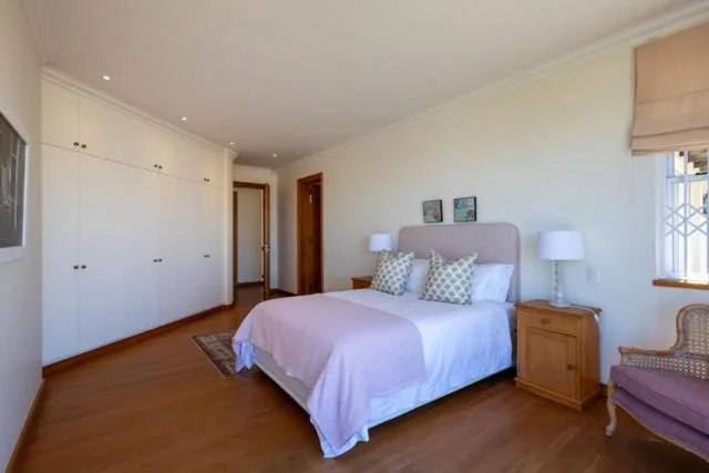 Spacious bedroom with queen bed, wooden furniture, and built-in wardrobes