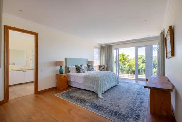 Spacious master bedroom with queen bed, garden views, wooden floors