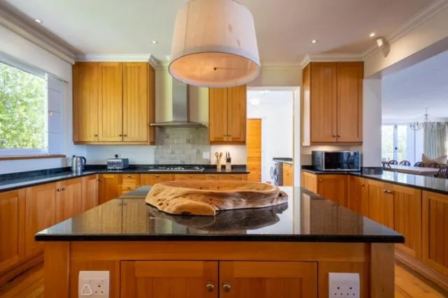 Spacious kitchen with wooden cabinetry, black countertops, island bench
