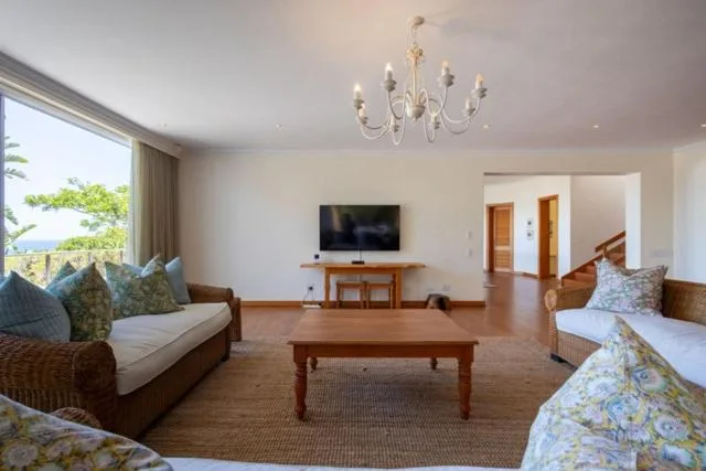 Spacious open-plan lounge with sofas, TV, and large windows overlooking garden