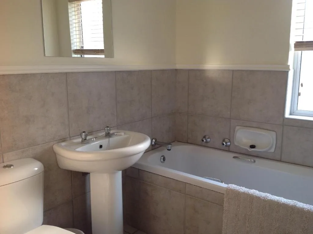 Spacious bathroom with pedestal sink, bathtub, and toilet fixtures