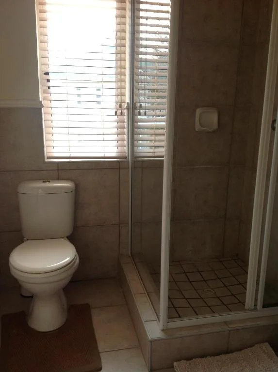 Bathroom with toilet, shower enclosure, and window with venetian blinds