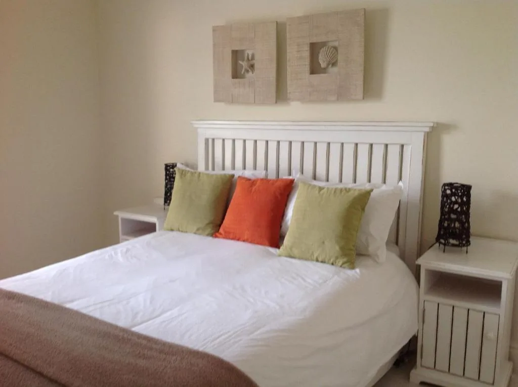 Bright bedroom with white wooden bed frame and colorful accent pillows