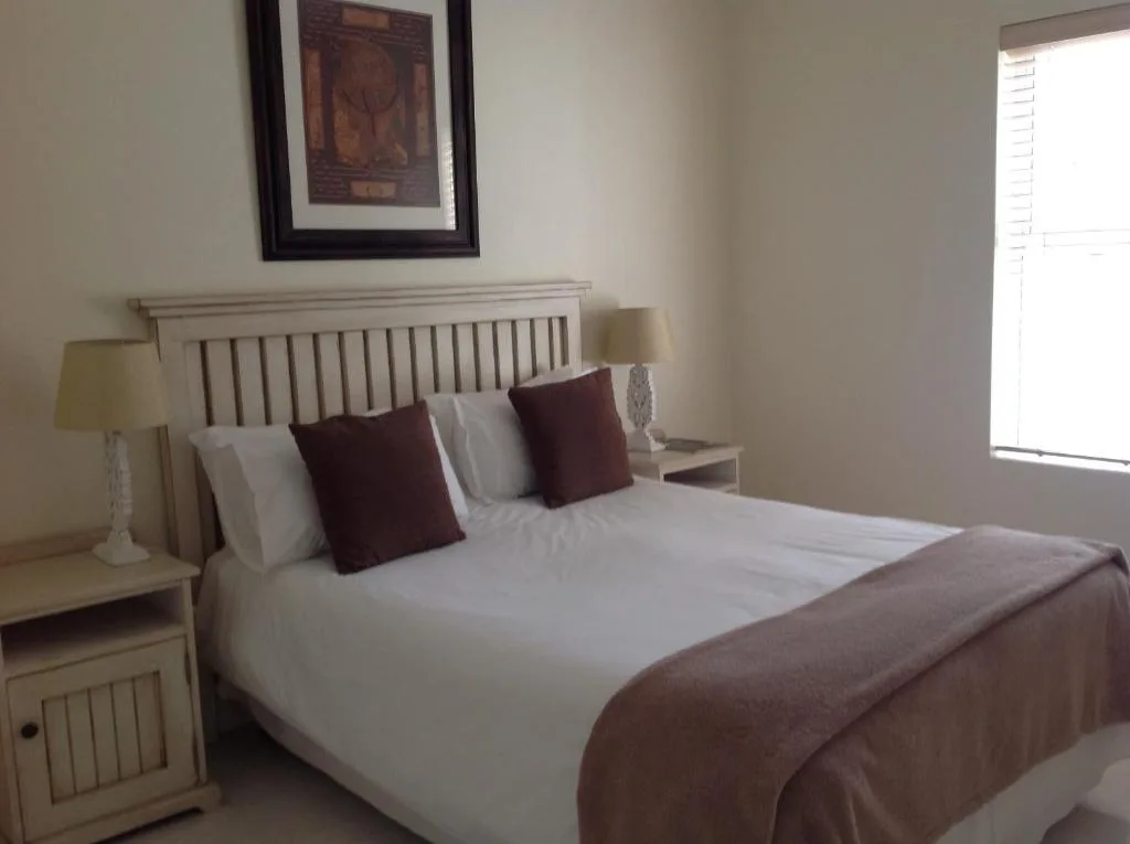 Spacious bedroom with wooden headboard, white linens, and burgundy accents
