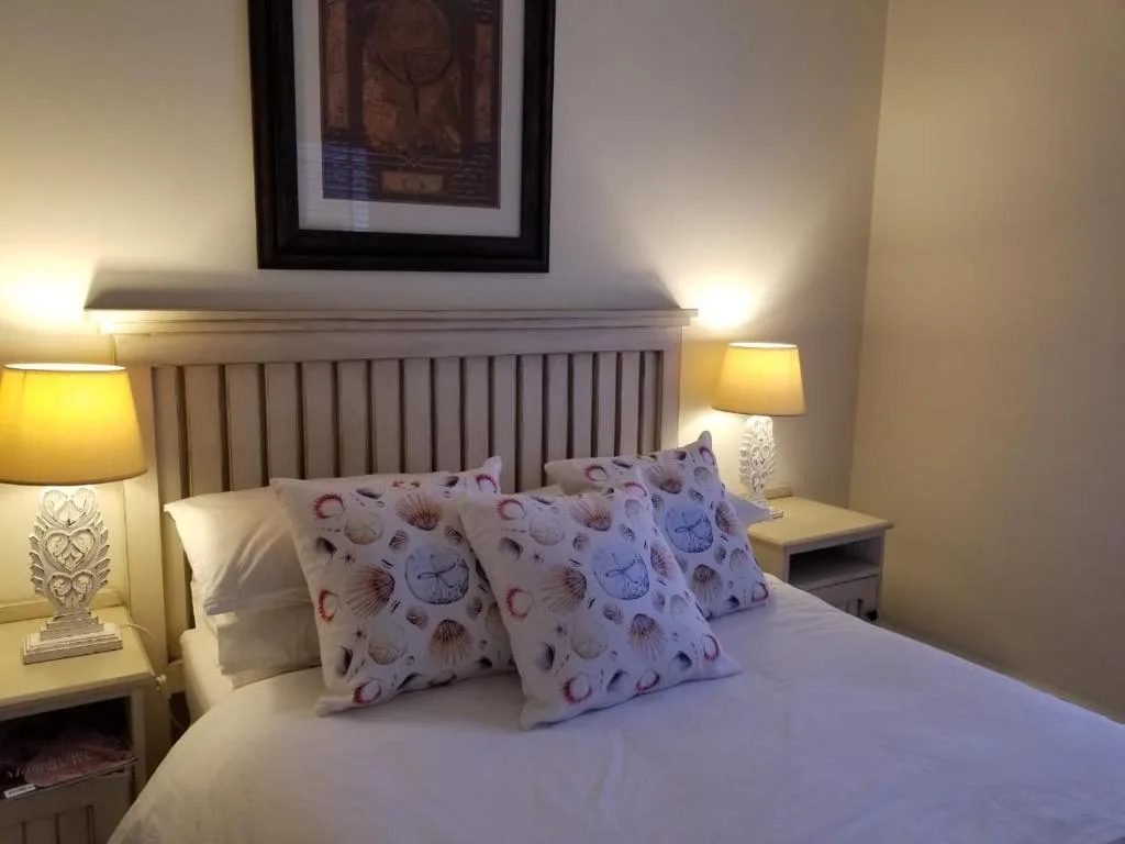 Comfortable bed with decorative shell-patterned pillows and bedside lamps
