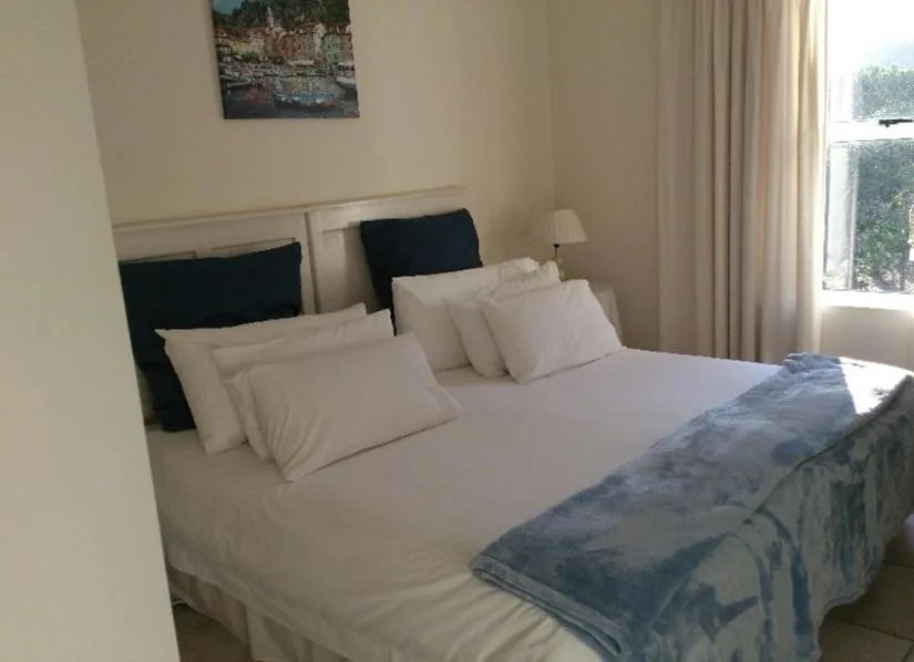 Bright bedroom with double bed, crisp white linens, and dark headboard