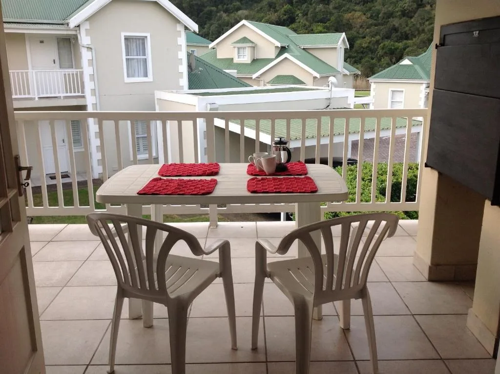 Outdoor dining table with chairs on tiled patio deck overlooking gardens