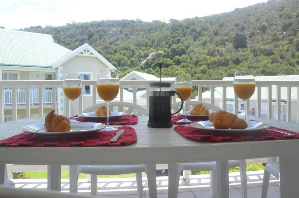 Breakfast setup on deck with coffee, croissants, and forested mountain views