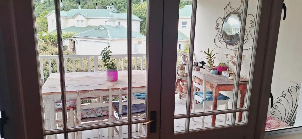 Wooden deck with potted plant and neighboring buildings visible beyond railing